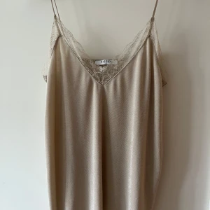 Beige linne från Pieces - Elegant beige linne från Pieces med spetsdetaljer vid halsringningen. Perfekt för en somrig dag eller en speciell kväll.