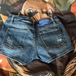 Blå jeansshorts från Crocker - Säljer ett par snygga blå jeansshorts från Crocker i storlek XXS. Shortsen har slitna detaljer. Otroligt lågmidjade på.