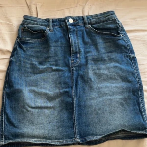 Jeanskjol från &Denim - Snygg jeanskjol från &Denim i klassisk blå färg. Kjolen har en normal passform med knapp och dragkedja framtill. Perfekt för en avslappnad stil.