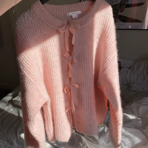 Rosa stickad tröja från Gina Tricot - Säljer en söt rosa stickad tröja från Gina Tricot. Tröjan har långa ärmar och en fin knytning framtill som ger en extra detalj. Perfekt för kyligare dagar och ger en mysig känsla. Passar bra till både jeans och kjol.