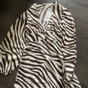 Zebramönstrad klänning från NA-KD - Säljer nu denna klänning då den inte kommit till användning. Klänningen är enbart provad och är i storlek 34! 