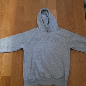 Grå hoodie från Gina Tricot med tryck - Säljer en tröja ifrån Gina Tricot.