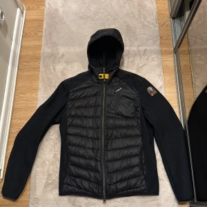Svart parajumper hybrid - Säljer min parajumper hybrid eftersom den inte kommer till användning längre. Jackan är äkta och köptes på jonells i storlek S för män. Jackan har använts några gånger men ser nästintill ny ut. Skriv vid funderingar eller frågor kring mera bilder.