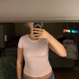 2-pack tighta bas-toppar i rosa & vitt - Säljer två stilrena, tighta bas-toppar i ett mjukt och stretchigt material. Ena toppen är ljusrosa och den andra är vit, båda med rund halsringning och korta ärmar. Perfekta att matcha med jeans eller kjol för en clean look.