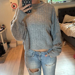 Grå croppad stickad tröja från pull&bear - Säljer en grå croppad stickad tröja från pull&bear.  långärmade, lite oversized ärmar. Super fin och passar till allt.  Tröjan är M men skulle säga att den är en S.