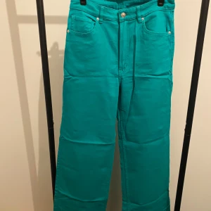 Turkosa jeansbyxor från H&M Divided - Snygga Gröna jeansbyxor från H&M Divided i rak modell. Byxorna har klassisk femficksdesign, bälteshällor och stängs med knapp och dragkedja. Perfekta för dig som vill sticka ut med färg. Materialet är bomull med lite stretch för skön passform.