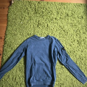 Blå långärmad tröja från Stone Island - Säljer en blå långärmad tröja från Stone Island med klassisk rund hals och ikonisk patch på vänster ärm. Tröjan är i mjuk bomull och har en clean, stilren look som funkar till jeans, Hör av dig vid frågor och funderingar, mvh Carl