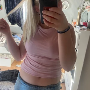 Ljusrosa croppad ärmlös topp - Säljer en ljusrosa croppad topp med ärmlös design och rund hals. Perfekt till jeans eller kjol för en chill och snygg look. Mjuk och stretchig, passar dig som gillar enkel men trendig stil. ( den är längre men uppvikt på bilden) storlek S 💞