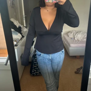 Svart långärmad omlottopp med djup v-ringning - Så snygg svart populär topp från Nelly som jag tyvärr säljer då den är lite liten i bysten.