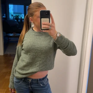 Grön stickad tröja från Vero Moda - Mysig grön stickad tröja från Vero Moda i storlek S. Tröjan har en rund halsringning, ribbade muddar och är långärmad. Perfekt för dig som gillar en enkel och chill stil. Passar till jeans eller kjol och är lätt att matcha med andra plagg.