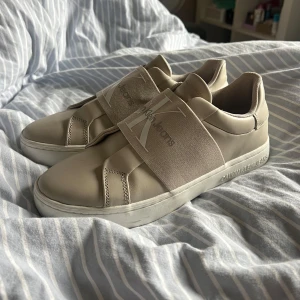 Calvin Klein sneakers  - Beigea sneakers från Calvin Klein. Köpta på Zalando och använda enstaka gånger (tror 1-2 ggr), så i väldigt bra skick. Storlek 40. Nypris cirka 700-900kr, säljs för 400kr. 
