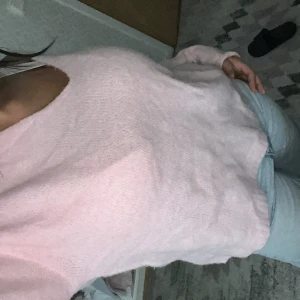 Ljusrosa stickad tröja med v-ringning - Säljer en supermysig ljusrosa stickad tröja med v-ringad hals. Tröjan har långärmade ärmar och en loose passform som gör den chill och enkel att styla med jeans eller kjol. Perfekt för dig som gillar softa pasteller och vill ha något bekvämt och snyggt.