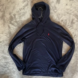 Mörkblå hoodie från Polo Ralph Lauren XS - Snygg mörkblå hoodie från Polo Ralph Lauren i storlek XS. Tröjan har huva med snörning och lång ärm, samt den klassiska röda broderade loggan på bröstet. Materialet är mjukt och tunt. Endast använd en gång. Nypris 1099kr