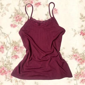 Vinröd ribbad linnetopp med spets - Supersöt vinröd linnetopp med tunna axelband och ribbad struktur. Toppen har en fin spetskant upptill som ger en extra detalj. Perfekt att styla med jeans eller kjol för en chill look.