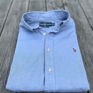 Blå skjorta från Ralph Lauren - ‼️Pris kan sänkas vid snabb affär‼️Säljer nu denna superfina Ralph Lauren skjorta! Nypris: ca 1200 kr. 100% bomull, 100% äkta. Skickar inom 24h efter du har köpt🚚. Knappt använd, näst intill nyskick. 