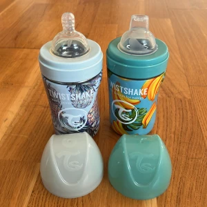 Nappflaskor  - Två nappflaskor med ananas ritning och banan. Nappflaskorna rymmer med 260 ml innehåll. De har olika nappar på flaskorna o har lock så att inget spils. Fina, söta o stiliga 