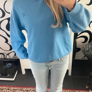 Blå sweatshirt från Acne Studios - Ljusblå sweatshirt från acne i storlek Xxs (men är oversized). Har en liten vit fläck på sig (se sista bild) därav priset.