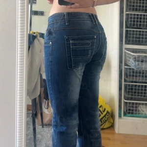 Blå bershka denim jeans - Säljer ett par snygga jeans från bershka med coola slitningar och klassiska detaljer. Jeansen har normal passform, låg midja och är tillverkade i mjukt denimtyg. Perfekta för dig som gillar en avslappnad men trendig look.
