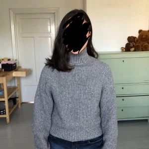 Grå polotröja i stickad ull från H&M - Säljer en grå polotröja från H&M i stickad ullmix, storlek XS. Tröjan har ribbad struktur, hög polokrage och långärmade ärmar. Perfekt för kyliga dagar och har en loose passform som är både chill och snygg.