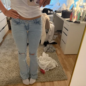 Lågmidjade bootcut jeans från Nelly  - Supersnygga lågmidjade ljusblåa bootcut jeans från Nelly med rosa detaljer på fickorna !! Hål vid knäna som en snygg detalj. 💞 storlek 34 (mycket stretchiga) är 169 cm för referens !