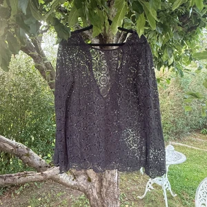 Svart spetsblus från Odd Molly - Svart blus från Odd Molly med lång ärm och v-ringning med knytband. Blusen är helt i spets med cirkulärt broderat mönster som ger en transparent look. Perfekt för dig som gillar detaljer och vill sticka ut med en unik topp. Storlek 2 som enligt deras storleksguide motsvarar en storlek M.  Mycket fint skick, jag hittar inga synliga anmärkningar eller defekter.