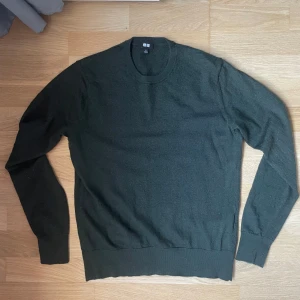 Mörkgrön merinoull stickad tröja från Uniqlo - En stilren mörkgrön stickad tröja från Uniqlo i storlek S men den passar xs mycket bättre. Tröjan har rund halsringning och långa ärmar, perfekt för lager-på-lager under kyliga dagar. Enkel och clean design som funkar till det mesta. Materialet är mjukt och skönt mot huden.