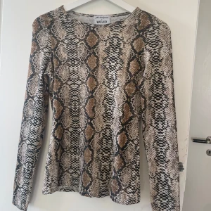 Snakeprint långärmad topp Madlady - Snygg långärmad topp från Madlady x Julia Bergman i ormskinnsmönster. Tight passform med beige, bruna och svarta toner. Skönt material och super snygg 🤩