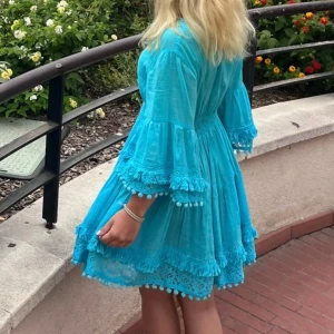 Turkos kortklänning med spetsdetaljer - SÅ otroligt fin turkos kortklänning med v-ringning, volangärmar och spetsdetaljer. Klänningen har broderade partier, tofsar och en luftig passform. Köpt i Frankrike 