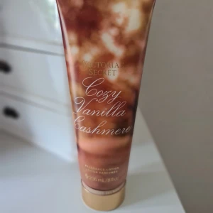 Victoria's Secret Cozy Vanilla Cashmere lotion - Parfymerad body lotion Cozy Vanilla Cashmere från Victoria's Secret. Doft av vispad vanilj, höstmysk och hasselnötsblomma. Tuben är brun med guldiga detaljer och rymmer 236 ml. Perfekt för dig som älskar varma, söta och mysiga dofter. Helt ny och oöppnad