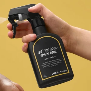 Lush Let The Good Times Roll Body Spray - En svart sprayflaska med gulddetaljer från Lush, doften Let The Good Times Roll. Body spray med söt, smörig popcorn-doft. Flaskan rymmer 200 ml och har en praktisk sprayfunktion. Perfekt för dig som gillar unika och lekfulla dofter.  Knappt använd