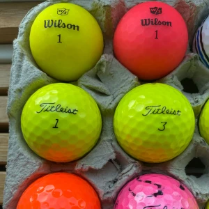 Färgade bollar (6pack - Bilderna visar färgglada golfbollar från märken som Wilson, Titleist och Nike, samt en boll med Brastad Golfklubb-logga. Perfekt för dig som vill sticka ut på golfbanan och ha kul med vänner! Säljs i blandade färger och märken.