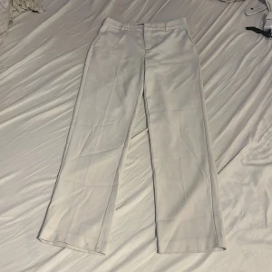 Vita kostymbyxor från Gina Tricot - Säljer ett par vita kostymbyxor från GinaTricot. Midwaist till låg midja och raka bak. (Endast använda på en skolavslutning)