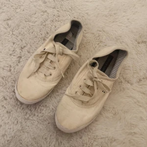 Vita tygskor  - Hej! Säljer dessa super fräscha vita tygskorna från Tommy Hilfiger då de helt enkelt inte kommer till någon användning längre. Skorna är i mycket fint skick utöver att dom är lite ”smutsiga” längst ut på toppen av skorna vilket man kan se på dom första två bilderna, är dock rätt så säker på att det är något som enkelt går bort i tvättmaskinen. Tveka inte på att höra av dig om du skulle ha några frågor, annars går det superbra att trycka på ”köp”.