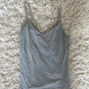 Grå linnetopp med smala axelband - Grå linnetopp med smala axelband och v-ringad hals. 