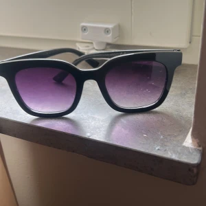 Svarta hjärtformade solglasögon - Säljer ett par svarta solglasögon med hjärtformade bågar. Glasen har en lätt toning och bågarna är i blank plast. Perfekt accessoar för att lyfta din stil med en lekfull touch.