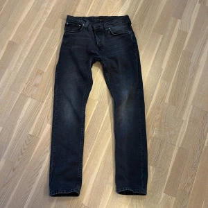  Nudie grim Tim dark cove jeans - Säljer ett par mörkgrå jeans från Nudie med klassisk femficksdesign. Jeansen har raka ben och subtila detaljer på bakfickorna. Perfekta för dig som gillar en stilren look med lite edge. Storlek W30 L32
