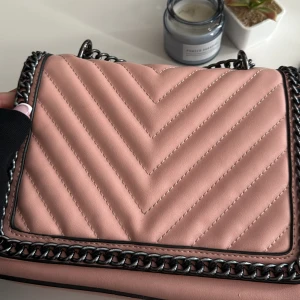 Rosa quiltad axelväska med kedja - Rosa axelväska med metall band. Rymlig väska funkar till vardag eller finare tillfällen 