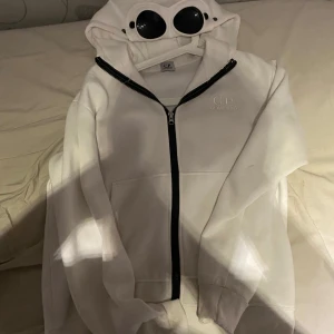 Vit hoodie från C.P. Company - Säljer en vit hoodie från C.P. Company med ikoniska goggles i huvan. Jätte bra skick. Pris kan diskuteras!