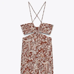 Långklänning med cut-out - Långklänning från Zara med paisley- och blommönster i beige och vitt. Klänningen har smala korsade axelband, snygg cut-out vid midjan och dragkedja i sidan. Endast testad!