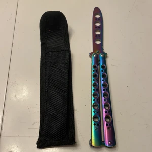 Leksak butterfly i regnbågsskiftande färg - Butterfly är gjord av rostfrittstål vilket ger den både hållbarhet och lätt vikt.Bladet är inte vasst vilket gör den bra till att öva tricks med!Det finns ett svart nylonfodral till för förvaring och skydd.Butterflyen har en regnbågsskiftande färg som gör den unik!