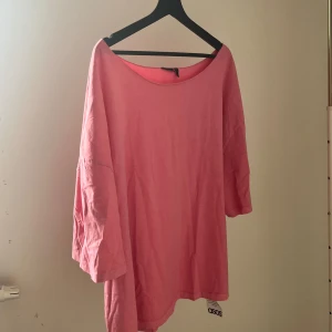 Oversized rosa tröja  - En oversized rosa tröja från ASOS med bred halsringning och trekvartsärmar. Tillverkad i mjuk bomull, perfekt för en chill och avslappnad stil. Enkel design utan mönster eller extra detaljer, passar dig som gillar loose fit och bekväma plagg.