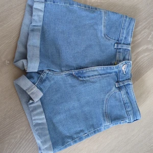 Ljusblå jeansshorts  - Snygga ljusblå jeansshorts Denim med klassisk femficksdesign och uppvikta benslut. Perfekta för varma dagar och enkla att matcha med allt. Gjorda i mjukt denimtyg för en avslappnad vibe.