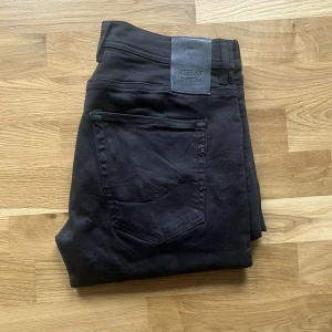 Replay Anbass Hyperflex jeans  - Säljer ett par svarta Replay Hyperflex jeans i storlek 31/34. Jeansen har klassisk femficksdesign, raka ben och är tillverkade i ett stretchigt material som ger extra komfort. Snygg svart tvätt och diskreta detaljer. Perfekta för dig som gillar stilrena och bekväma jeans. Längd ca 115cm