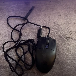 En data mus som lyser  - Bilderna visar en svart datormus med USB-kabel, troligen avsedd för gaming eller arbete vid datorn. Produkten är inte en bok och saknar omslag, titel eller författare.