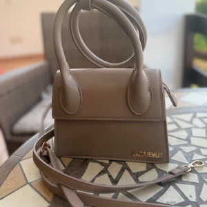 Beige Jacquemus handväska i skinn - Superfin beige handväska från Jacquemus med stilren design och guldigt logodetalj framtill. 