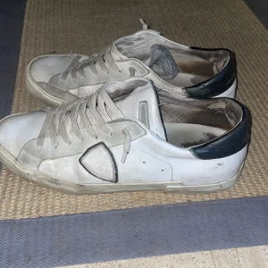 Philippe Model PRSX - Ett par Snygga vita Philippe Model low-tops med svart detalj på hälen och klassisk snörning. Skorna har en rund tå och platt sula, tillverkade i skinn med inslag av mocka. Perfekta för en clean och stilren look. Ett småtal defekter bland annat innanför skon och lite där bak på hälen, men verkligen inget som syns vid användning. Därav priset. 7,5-8/10 i skick , Pris går att diskutera. Allt OG ingår. Skriv vid minsta lilla intresse!