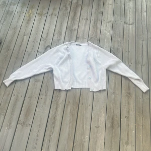 Ljusblå ribbad kofta från Gina Tricot - Superfin ljusblå kofta från Gina Tricot i ribbstickat material. Croppad modell med långa ärmar och stora knappar framtill. Perfekt att slänga över en topp för en chill look. Materialmix av viskos, polyester och polyamid.