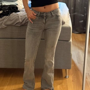 Grå bootcut jeans  - Säljer ett par grå jeans med bootcut passform. Jeansen har klassisk femficksdesign, låg midja och är tillverkade i mjukt denim. Perfekta för dig som gillar en avslappnad men ändå snygg stil.