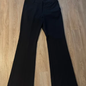 Svarta bootcut-byxor Junkyard S - Snygga svarta kostymbyxor från Junkyard i storlek S. Byxorna har klassisk passform med utsvängda ben och är tillverkade i ett mjukt material av polyester, viskos och elastan. Perfekta för en stilren och trendig look. Aldrig använda men saknar prislapp då jag tog bort den innan jag provade de.