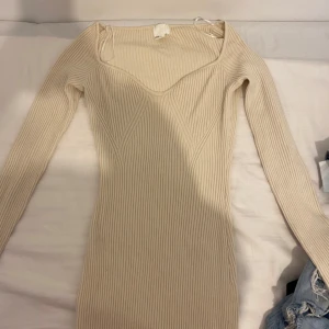 Ribbad beige långärmad klänning, pris kan diskuteras - Snygg ribbad klänning i beige med lång ärm och figurnära passform. Klänningen har en v-ringad urringning och är tillverkad i ett stretchigt material som sitter tight. Perfekt för dig som gillar stilrena och enkla plagg med en modern touch. Jag är 175 och den är lite över anklarna både denna och den svarta är knappt använda.